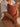 Child holding a brown cushion against a neutral background