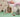 Children's room with a dollhouse, toys, and a bed with pink bedding.