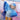 Child in a blue and silver costume with ruffled sleeves and skirt, sitting on a pink surface.