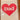 A square greeting card with a large red heart and the word 'Dad' in white, photographed on a wooden surface inside a clear protective sleeve.