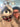 Person wearing glasses and a beret with a large fluffy toy racoon wearing a plaid scarf.
