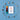 A flat-lay of a white art print with the text 'BAM! CREATE YOUR TRANSPORTS' and a small illustration, surrounded by small wooden stamp blocks arranged in a circle on a blue background. To the left of the print are four vertical color blocks in orange, rust red, black, and teal.