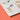 A close-up of a printed card or booklet page showing illustrated animal figures with small text, placed on a solid orange surface.