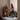Gnome figurine with a red hat and green sweater next to a gingerbread house with small figures on a neutral background.