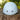 A light blue helmet with ventilation holes, resting on a rustic wooden tree stump with a blurred green outdoor background.