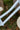 Close-up of a bicycle frame in a pale icy blue with tiny scattered gray and yellow floral motifs, featuring the brand name 'rotale' printed in white on the down tube, set against a blurred outdoor background of green foliage and brown tree trunks.