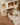 Child playing with a dollhouse made of wooden blocks on a carpeted floor.