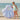 Child in a swimsuit standing next to an inflatable seashell float on a beach.