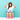 A young girl with long dark hair smiles while standing behind a colorful magnetic building block castle on a white table against a light blue background.