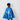 Child wearing a blue superhero cape with star, planet, and lightning bolt designs on a white wall.
