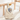 Knitted goose toy with a smaller toy inside, on a wooden crib.