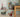 Decorative items including a duck, gnome figures, and sleighs on a wooden floor against a light green wall.