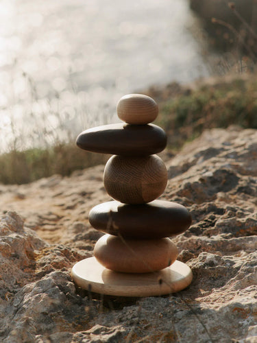 Stack of wooden pebble stones on a rocky surface with a blurred natural background