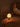 Lamp on a wooden table in a dimly lit room with a bed in the background