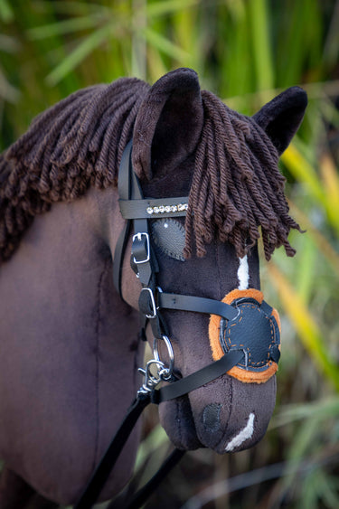 Close-up of a hobby horse head with a bridle in a natural setting