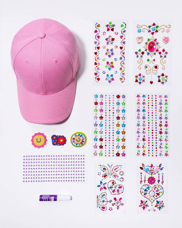Pink cap with colourful stick on jewels, glue and transfers on a white background