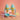 A pastel-colored play dough set featuring two soft-serve ice cream cones in yellow cones on a light blue stand, with a matching scoop and melting pink and yellow ice cream puddles on a peach background.