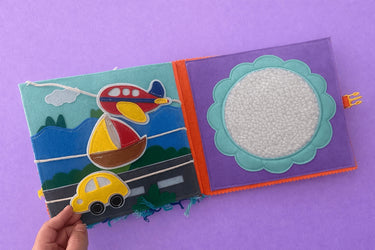 Children's activity book with colorful illustrations of a plane, car, and road on a purple background