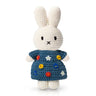 Crocheted bunny toy wearing a blue dress with colorful flower patterns on a white background