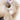 Close-up of a plush toy with a gold button and pearl detail on a white background