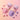Two stand-up pouches of Wonder Dough Mix, one pink and one purple, with piles of matching colored powder spilled below and small rolled dough pieces arranged around them on a soft pink background.