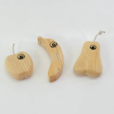 Wooden musical shakers in the shape of an apple, banana and pear on a white background 