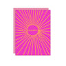 A bright pink congratulations card with a matching pink envelope behind it. The card features a bold yellow-orange sunburst design radiating from the center, with the word 'CONGRATS' written inside a circular motif.