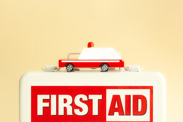 A wooden toy ambulance sitting on a first aid boix 