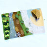 Felted landscape with trees, rocks, and a cave on a white background