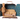 Maileg Reindeer in Suitcase Little Sister, a 16cm patterned suitcase opening on a reindeer's sofa bed and rug