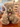 A fluffy light gray and sparkling teddy bear plush toy sitting on a wooden table in a shop, with a hangtag attached and another teddy bear blurred in the background. He is labelled Bear C.