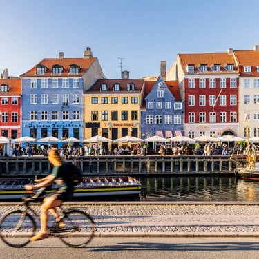 Colorful buildings along a canal with a cyclist in the foreground.