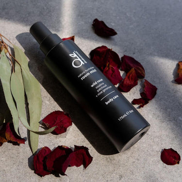 Black bottle of room mist with dried leaves and eucalyptus on a textured surface