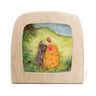 A wooden Toverlux lamp with rounded corners and a clear front window, showcasing a handcrafted felted wool art piece of a gray bunny next to an orange Easter egg on a green hill under a blue sky.