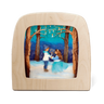 A Toverlux lamp with rounded corners, featuring a hand-painted winter forest scene on the front. The artwork depicts a boy and a girl in a snowy landscape under a tree with hanging candles, set against a light wood frame on a white background.