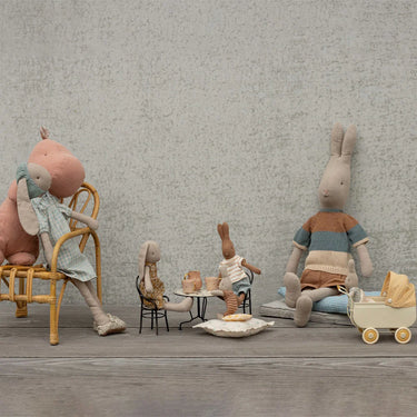 Set of toy rabbits and a rabbit with a baby in a room with a textured wall.