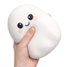 A hand holding a white, squishy, bean-shaped stress toy with a cute cartoon face featuring black eyes and a smiling mouth, with pink rosy cheeks, against a plain white background.