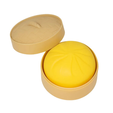 Yellow dumpling squish in a beige steamer container on a white background