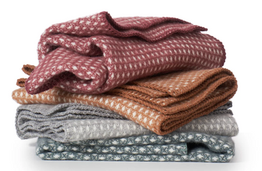 Stack of folded blankets in various colors on a white background