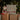 Gift box with Christmas design, small doll, and wrapped present in front of a decorated tree.