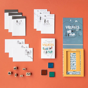 Collection of 'Villages' themed stationery items on an orange background, including stamps, a workbook and coloured stamp pads. 