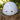 A white safety helmet with ventilation holes and a circular 'Z' logo, resting on a rustic tree stump with a blurred green forest background.