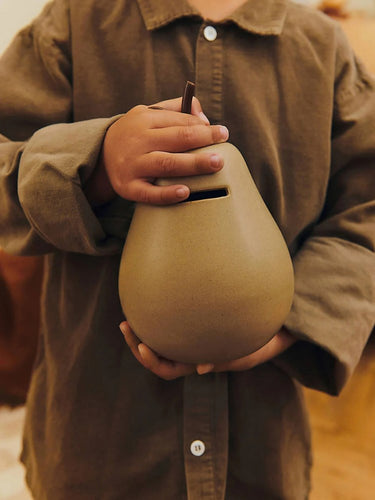 Person wearing a brown shirt holding a Ferm Living money bank