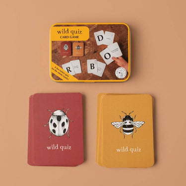A card game called wild quiz in a metal tin, with red beetle cards and yellow bee cards on a beige background 
