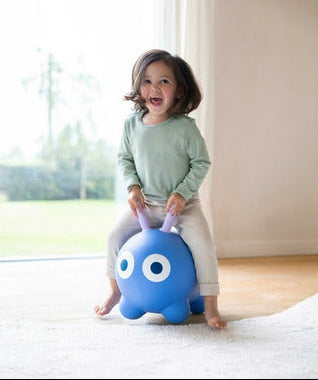 Child sitting on a blue bouncy seat with a white background