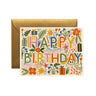 A square greeting card with a colorful floral 'HAPPY BIRTHDAY' design, shown in front of a gold envelope on a white background.