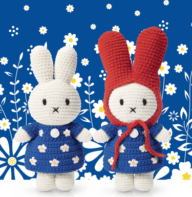 Two crocheted rabbit toys with blue dresses and red hats on a floral background