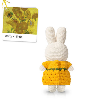 White rabbit toy with yellow dress and sunflower design, standing next to a branded card.
