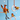 Three plush bird toys hanging from wooden rings and a wooden perch against a light blue background.