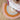 Round rainbow-colored rug on a wooden floor with a white textured blanket.